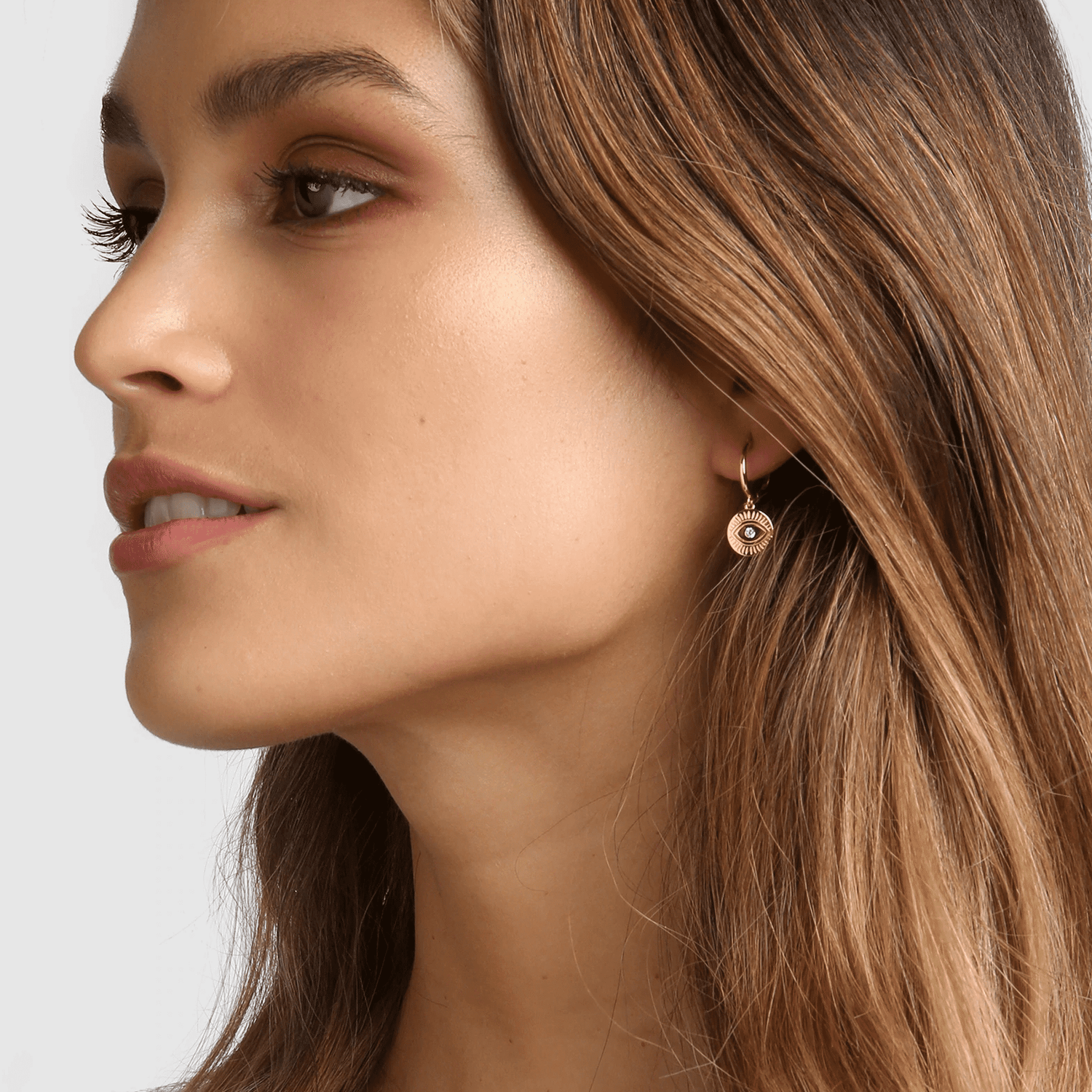 arms of eve protective eye gold hoop huggies earrings on model